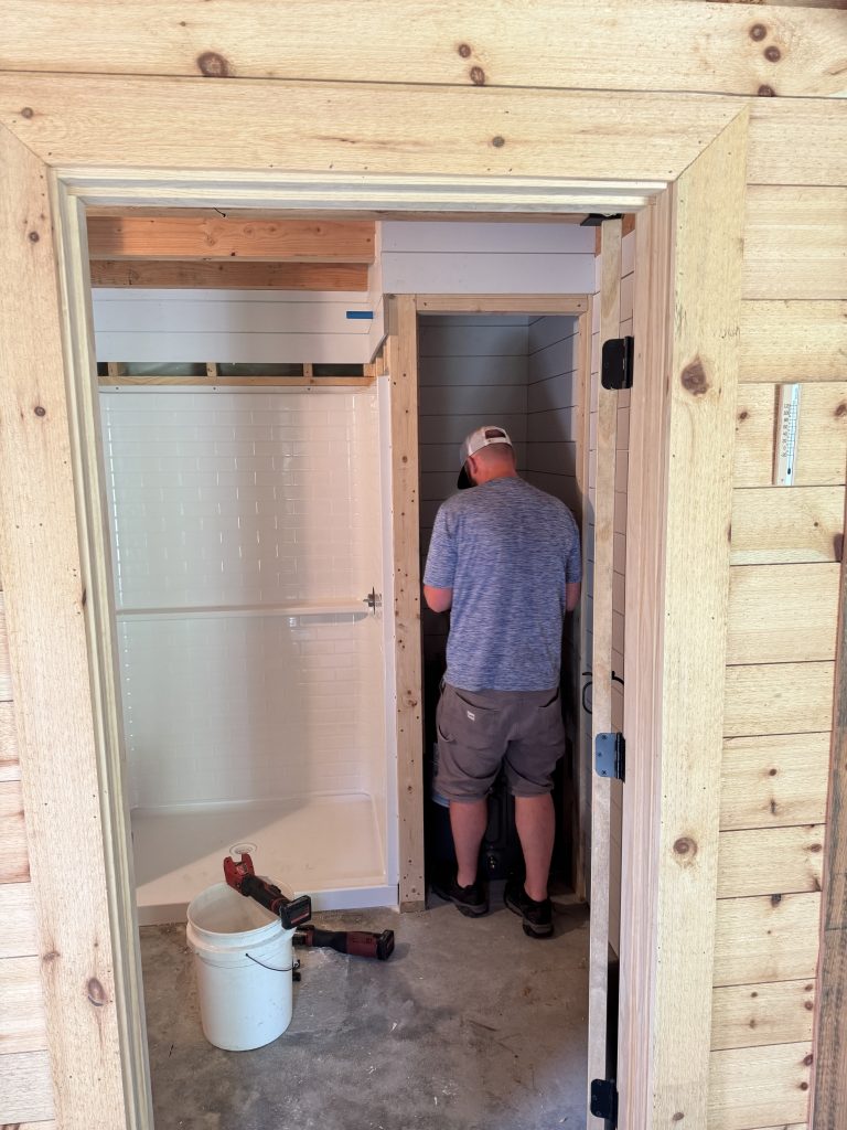 Person painting inside an unfinished bathroom.