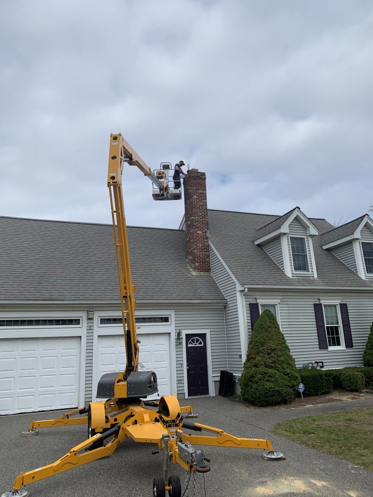 Worker using a lift to access a house chimney.