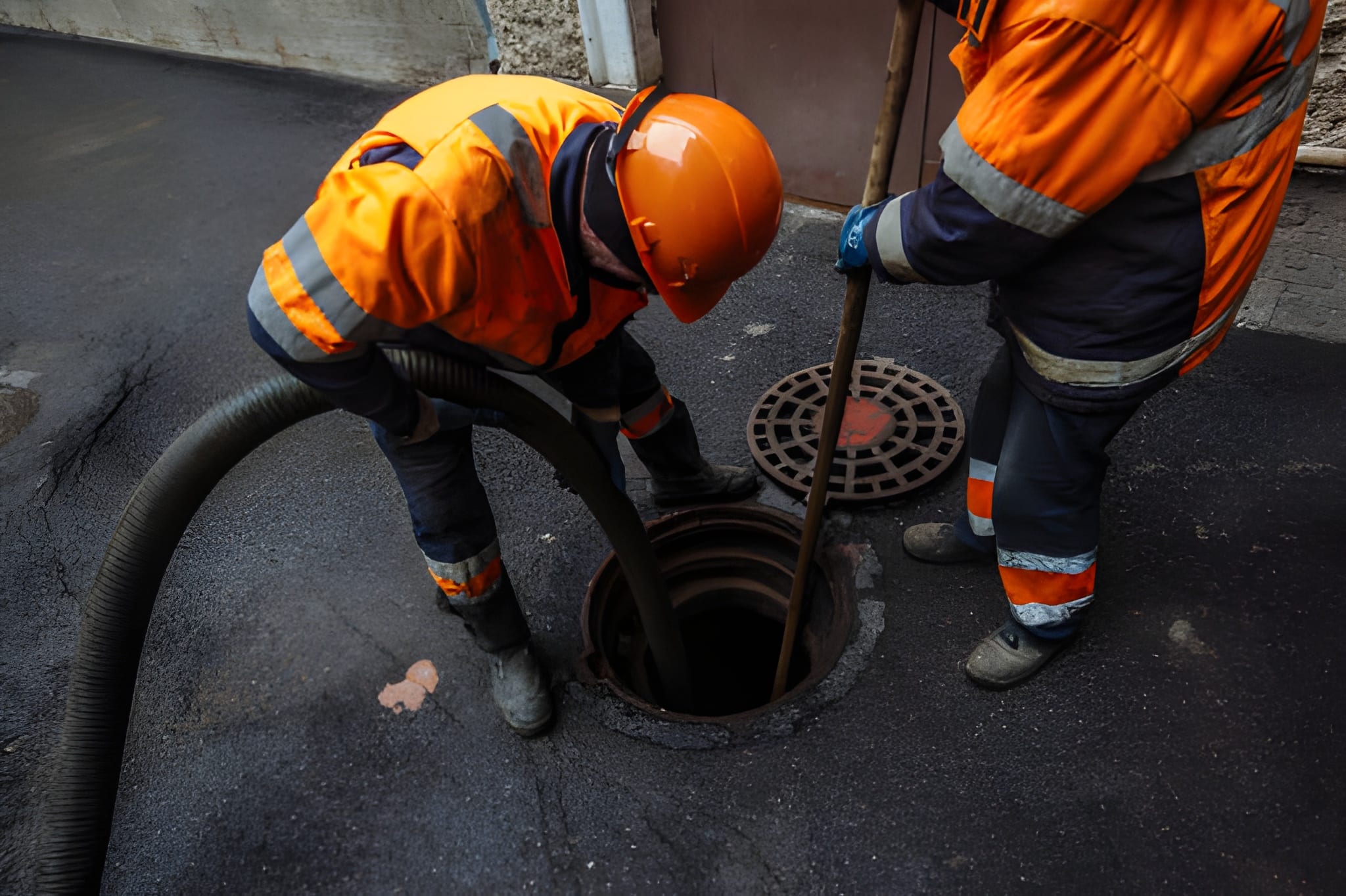 Sewer workers cleaning manhole and unblocking sewers the street sidewalk.