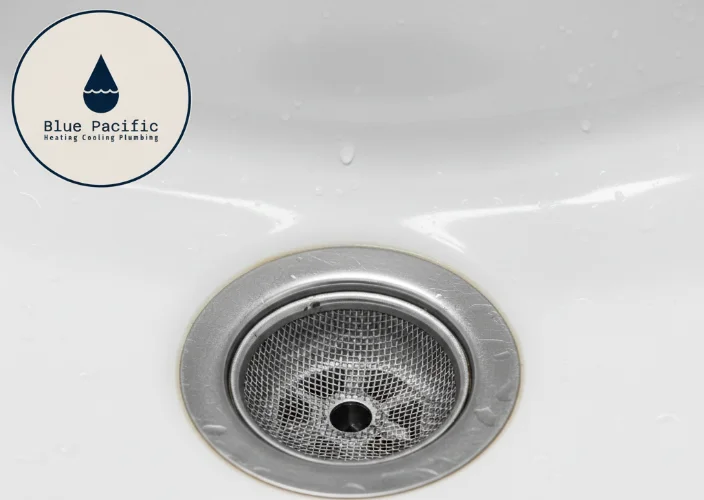 Close-up of a clean bathroom sink drain with a mesh strainer.