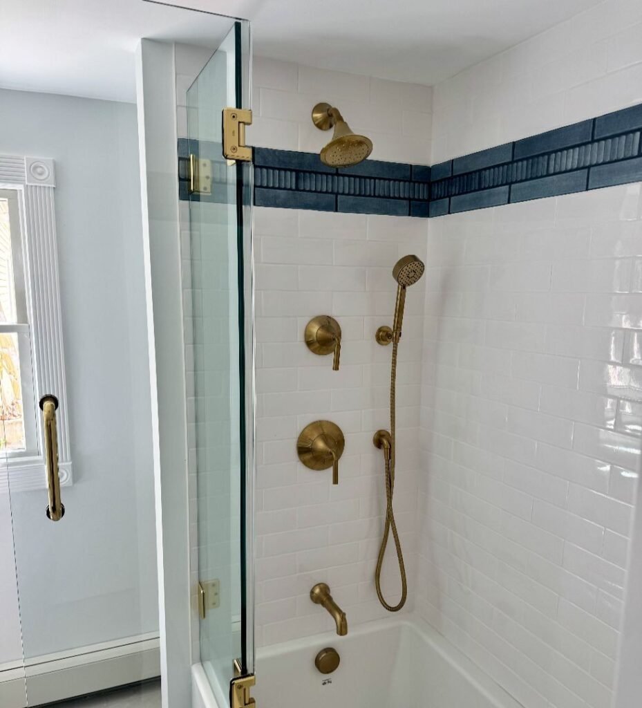 Modern shower with brushed brass fixtures and subway tile