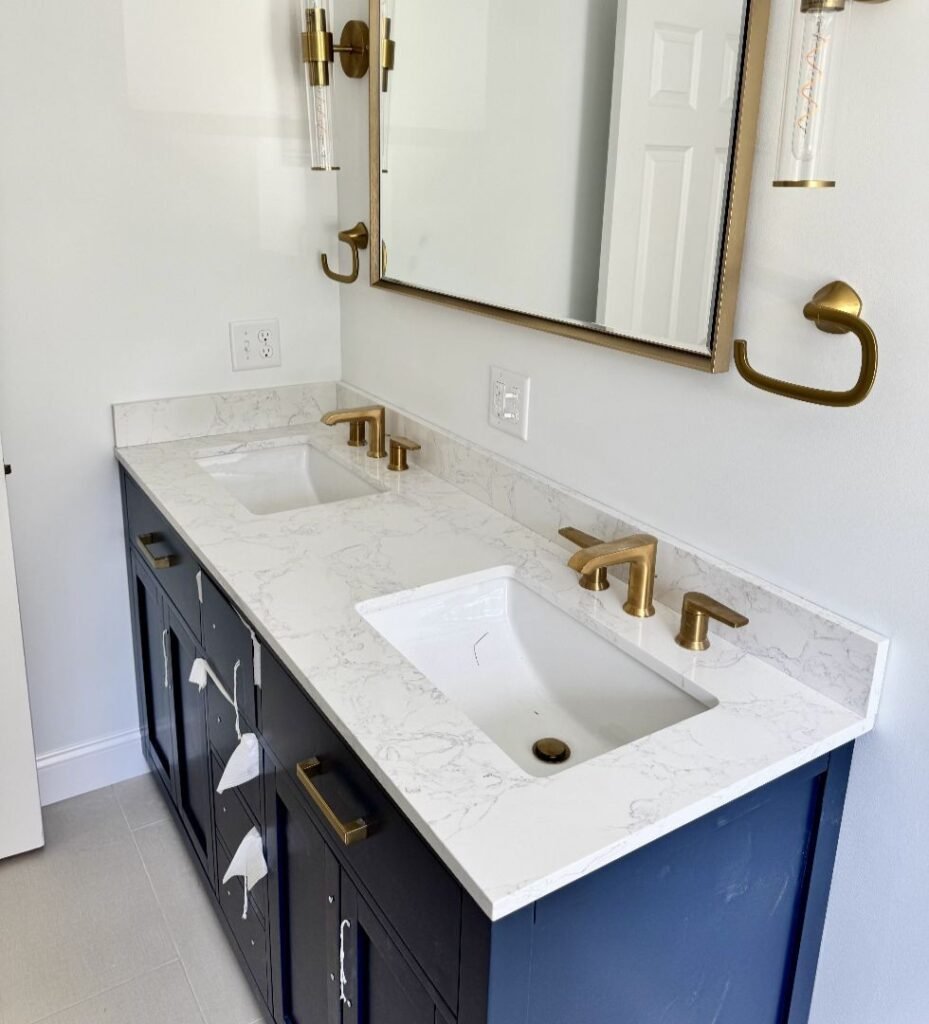Gallery: Modern navy vanity with white marble countertop and brass fixtures in a bathroom.