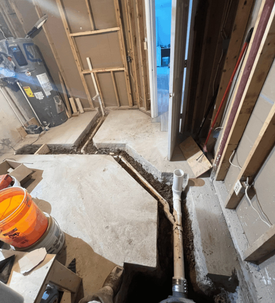 Plumbing rough-in for a bathroom remodel, showing pipes in concrete.
