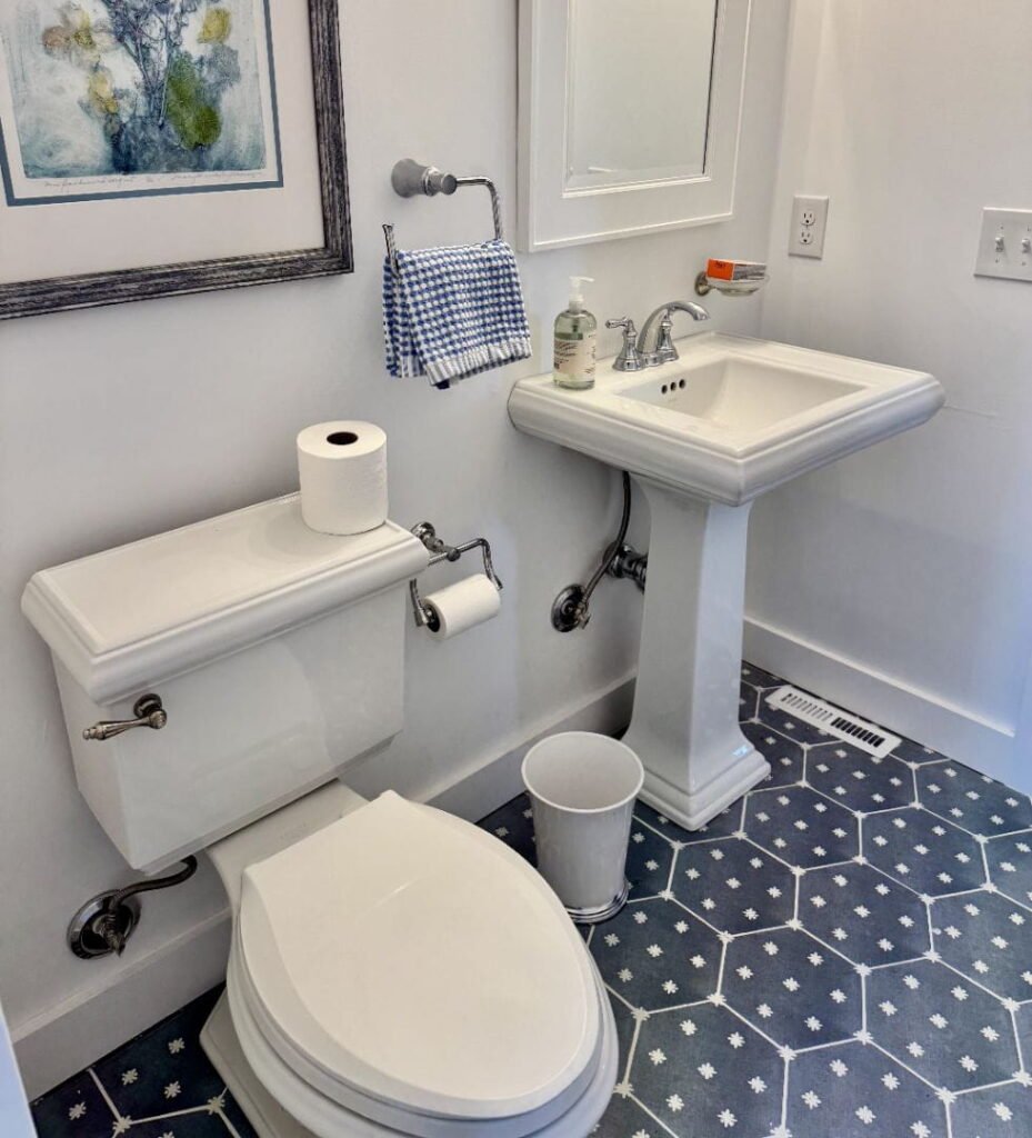 A clean, modern bathroom with a white pedestal sink, toilet, and hexagonal tile floor.