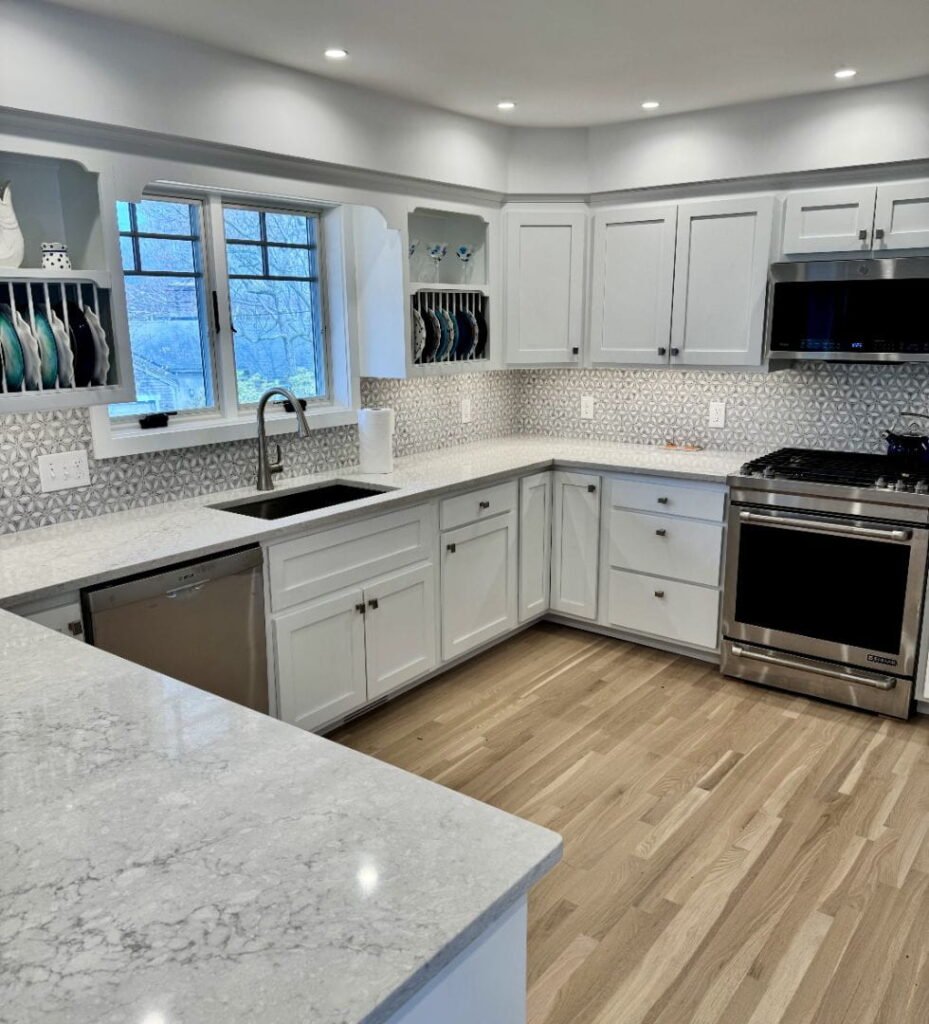 Modern white kitchen gallery with gray geometric backsplash and stainless steel appliances.