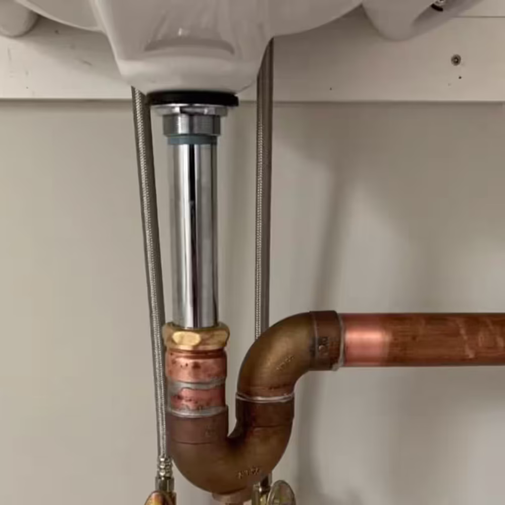 Close-up of sink plumbing with copper P-trap and drain pipes.