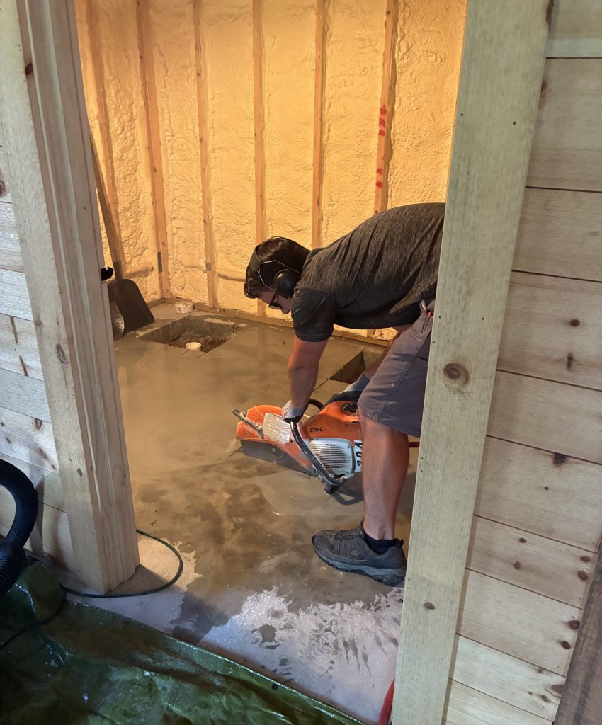 Person working inside a framed wooden room.