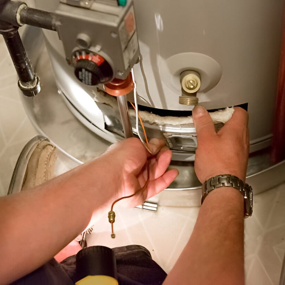 Man shines flashlight on hot water heater