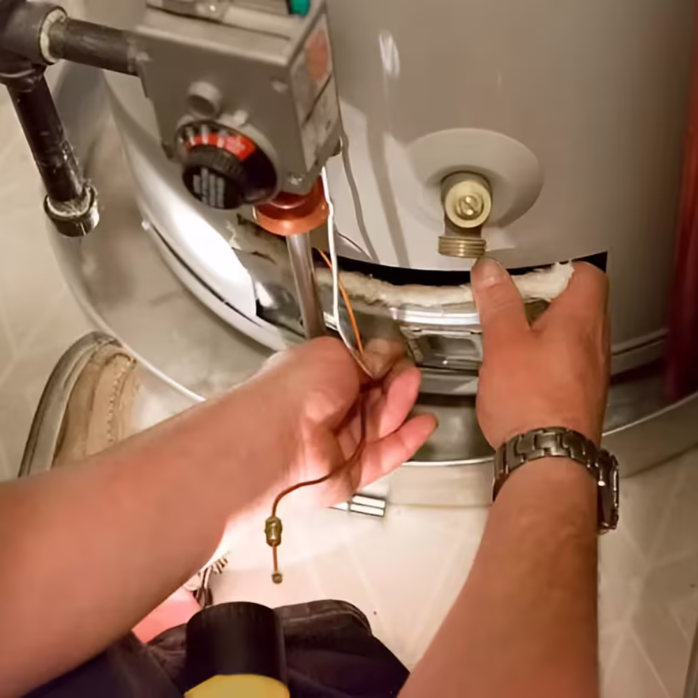 Plumber's hands adjusting a water heater pilot light assembly.