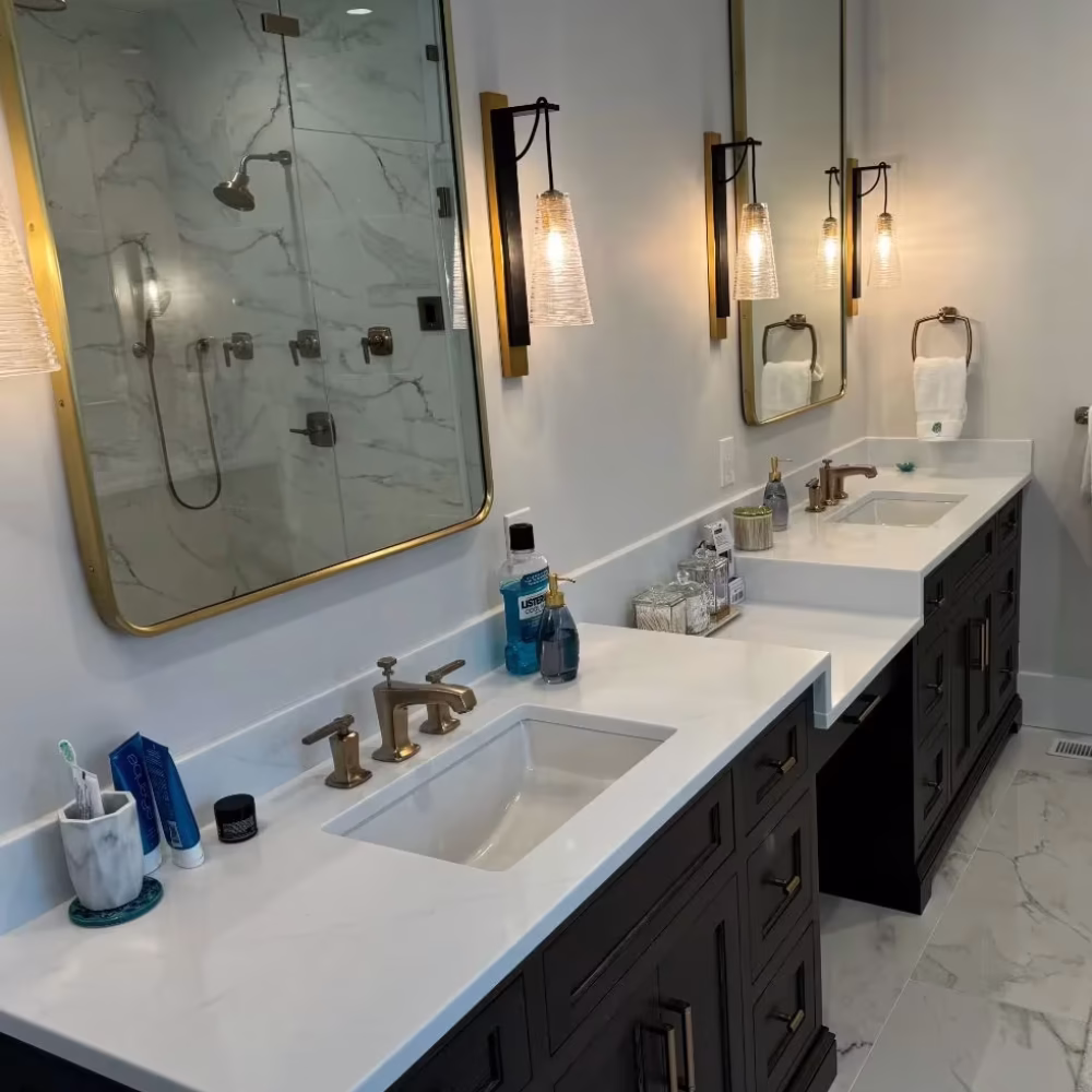 Modern bathroom with double vanity, brass plumbing fixtures, and marble shower.